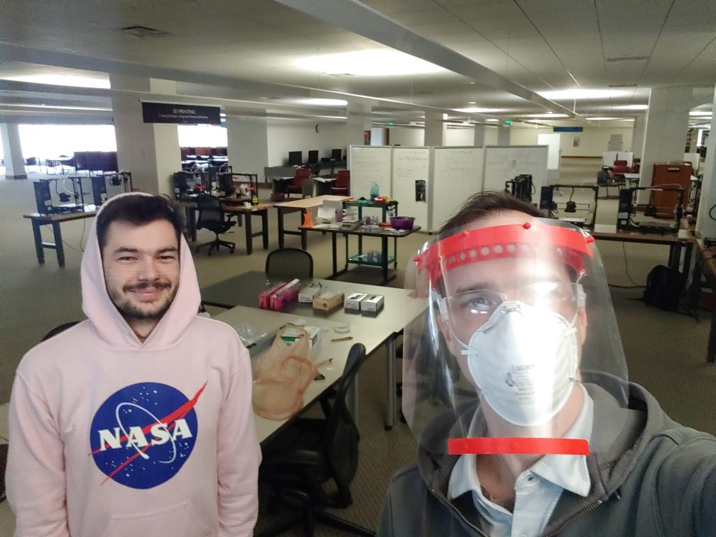 Two library staff, one smiling and the other with a face shield and mask