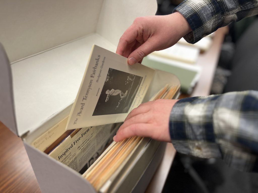 An image of Alex's hands reaching into a filing box. In his right hand he holds a historical pamphlet.