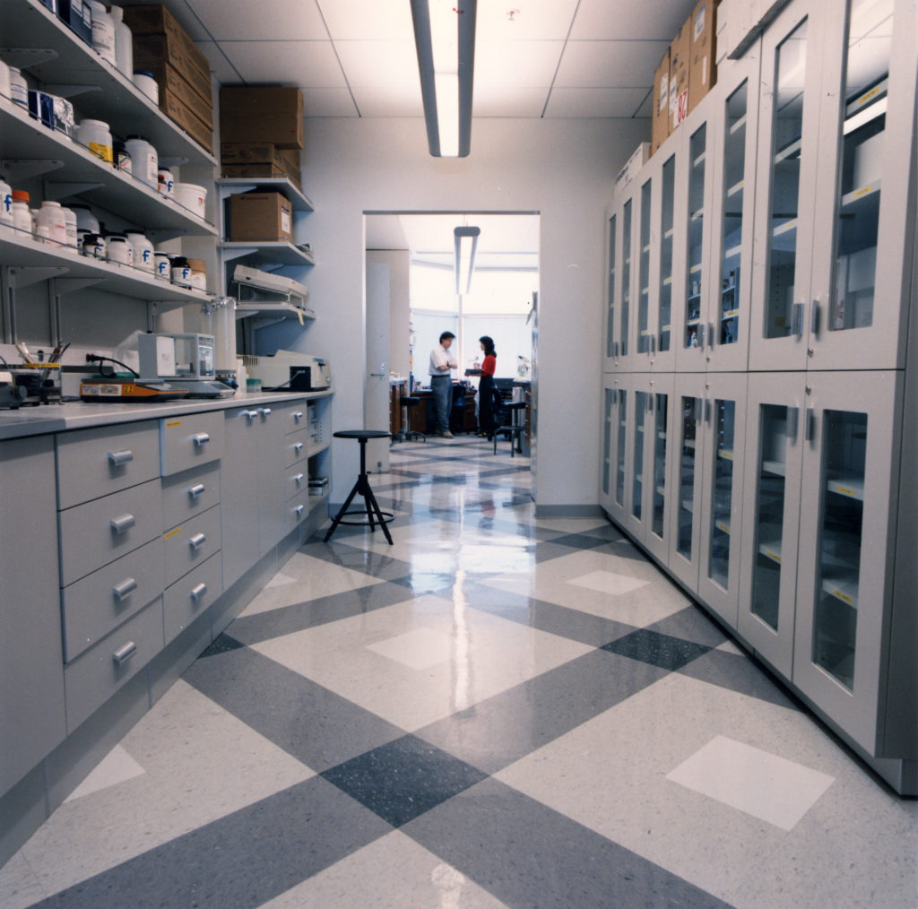A hallway in the Medical Genetics lab. Two people face each other while speaking at the end of the hall.